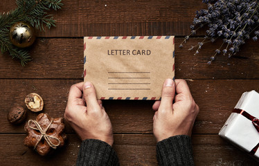 Close-up of male hands holding envelope with invitation for Christmas holidays. Concept of greeting...