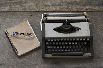 Old typing machine and glasses with book notes on wooden backgro