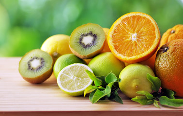 Citrus fruits, kiwis and leaves on table