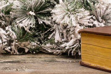 Old book and fir branch in snow on wooden table