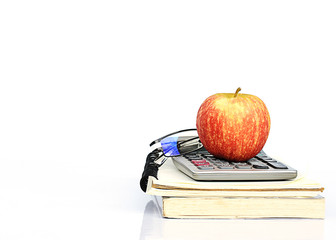 Red apple fruits on book stack and calculator and glasses with h