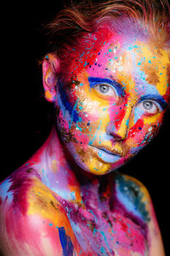 Portrait of a woman with colorful paint brushstroken on face. Bright blue eyes. Advertising Space