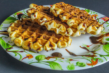 Viennese waffles topped with chocolate in a plate on  dark background