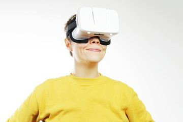 Teenager with virtual reality headset is stunned by VR experience. Teen smiling wearing in vr glasses on a white background. New technologies and young person.