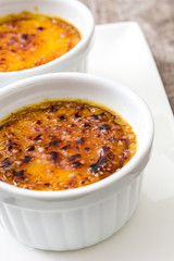 Traditional French creme brulee dessert with caramelized sugar on top, on wooden table

