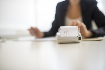 Adding machine in foreground with obscured worker