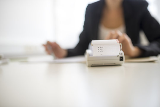 Adding machine in foreground with obscured worker