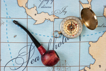 tobacco pipe and compass on map