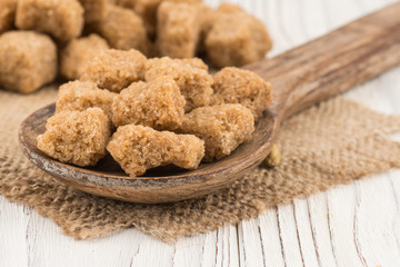 Brown sugar in a wooden spoon on the old wooden table.