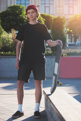 Young man holding skateboard. Skater standing outdoors. My sport is my passion. Against the grain.