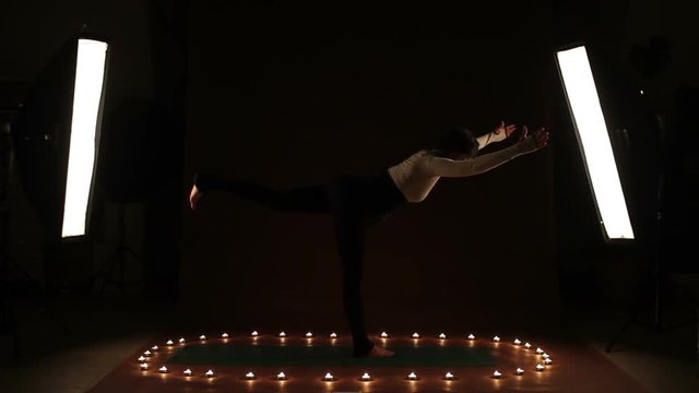 A young woman showing gymnastic exercise in the dark