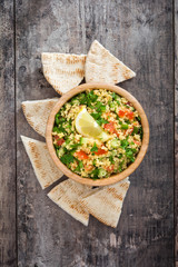 Tabbouleh salad with couscous and pita bread on a rustic table

