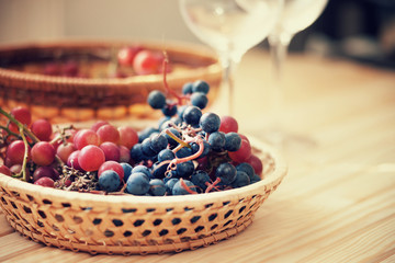 Grape in the wicker basket and empty wine glasses 