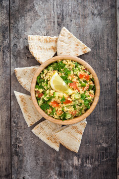 Tabbouleh salad with couscous and pita bread on a rustic table

