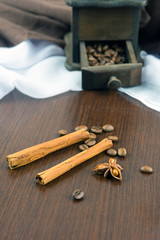 Coffee beans with cinnamon sticks and anise on brown table.