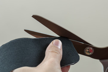 Physiotherapist cutting on black kinesio tape with a scissors