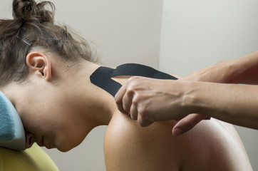 Obraz na płótnie Canvas Physiotherapist putting on black kinesio tape on woman patients