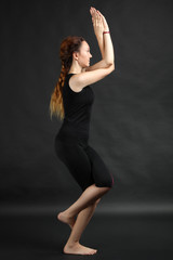 Fototapeta na wymiar Young beautiful yoga posing on a black studio background
