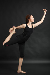 Young beautiful yoga posing on a black studio background
