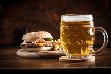 A glass of fresh cold light beer with gourmet hamburgers and wheat in a bar and a dark pub
