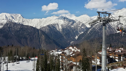 Winter ski resort, cable way, cottage village, snow-capped peaks of the Caucasus Mountains