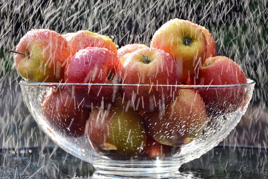 szklana misa z czerwonymi jabłkami w strugach deszczu