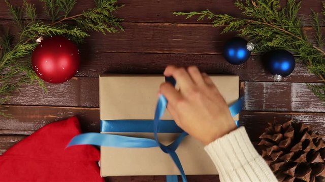 Top view man unwrapping christmas presents at wooden desk hands from above