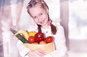 Pretty girl holds paper bag with vegetables and fruits