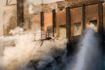 Smoke enveloping staircase while firefighters spray water into burning building downtown Chicago