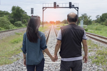 Couple holding hands with railway in background