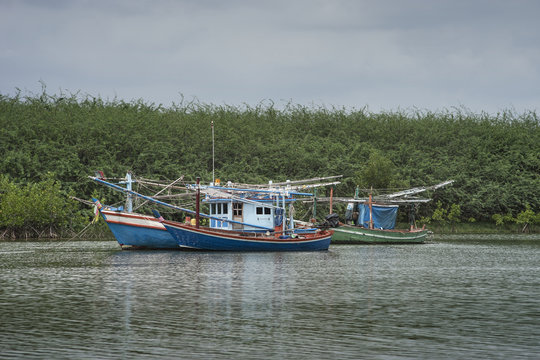 traditional fishing boat on the sea with mangrove forest in background.cloudy sky.filtered image.selective focus