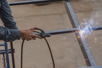 Welder works on steel roof .