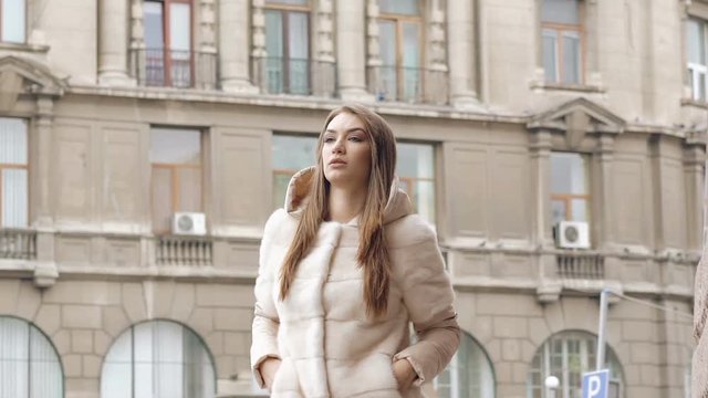 Stylish woman in furry coat walks runway and posing on the street. Slowly