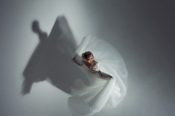 Beautiful attractive bride in wedding dress with long full skirt, white background, dance and...