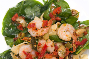 close up on fresh salad of prawns, pasta, baby spinach and chili,  on white