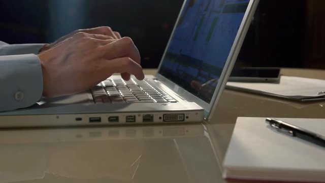 Close-up of lap-top computer and a man typing something on it