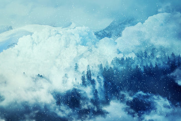 Fantastic winter background with an avalanche in the snowy mountains. Beautiful landscape mist and snowfall in the fir forest. Travel inspiration.