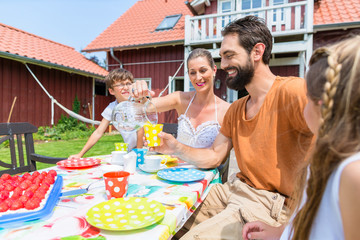 Familie mit Kuchen im Garten in Sommer