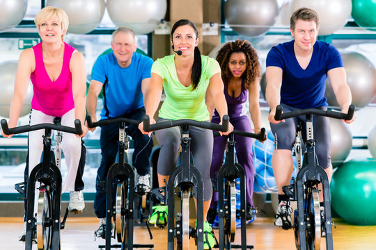 Fitness group of men and women spinning of bike in gym