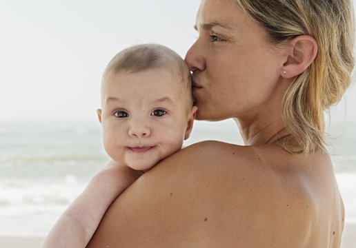 Mother kissing her baby girl on the beach