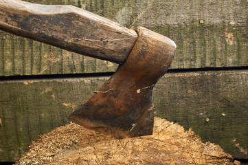 Axe stuck in a firewood on a wooden background. Big old woodcutter's ax. A piece of wood for the fire deck.
