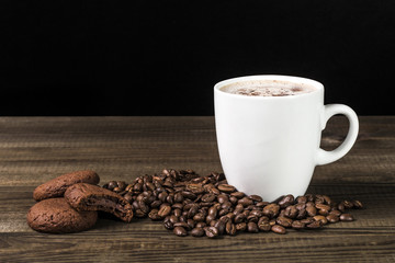 cup of coffee with coffee beans and cookies on wooden table