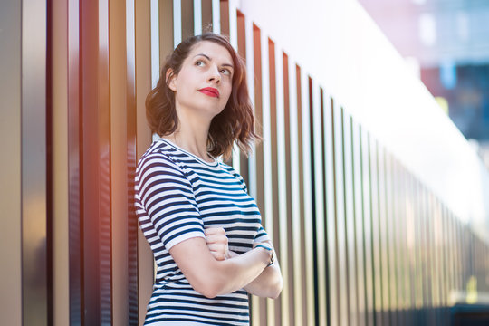 fashionable young woman looking up, hopeful and dreamy, posing in modern surrounding.

