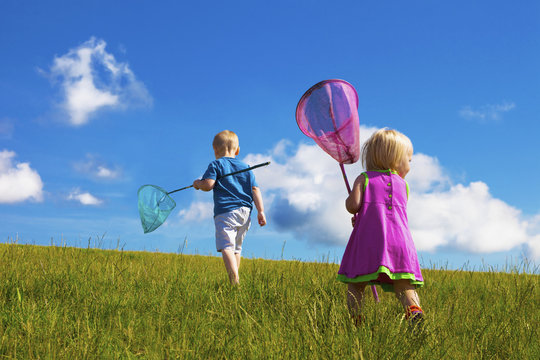 A Young Boy And Girl Walk Through A Field With Butterfly Catchers; Stony Plain, Alberta, Canada