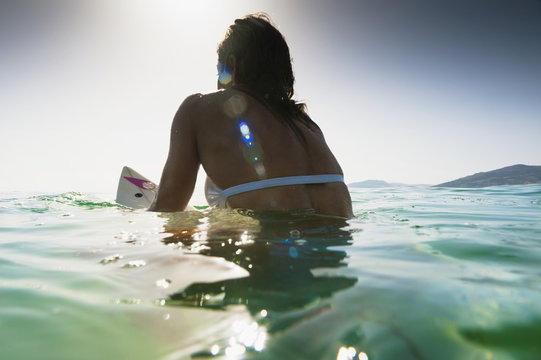 A Woman Sitting On A Surfboard In The Water; Tarifa, Cadiz, Andalusia, Spain