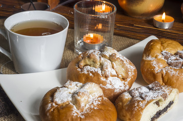 kompozycja z kołaczykiem drożdżowym makiem serem i rodzynkami na białym talerzyku i drewnianymi elementami, yeast dough with poppy seeds