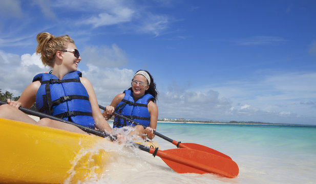 Two Women In Lifejackets Paddling In A Yellow Boat; Punta Cana, La Altagracia, Dominican Republic