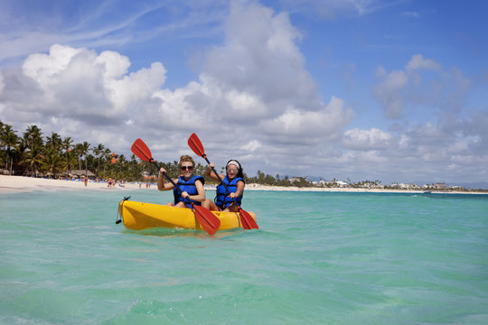 Two Women In Lifejackets Paddling In A Yellow Boat; Punta Cana, La Altagracia, Dominican Republic