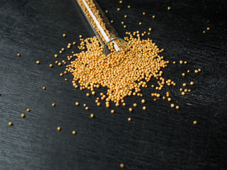 Seeds of white mustard spilled from glass tubes on a dark background

