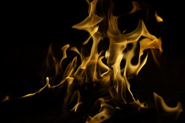 Snapshot of yellow, flickering tongues of fire dancing and twisting on black background